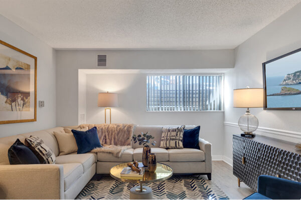 Living room with large rug, sectional couch, eclectic furniture and lamps, and large window.