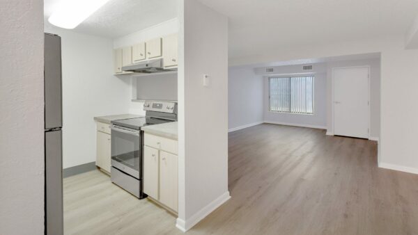 Living area with wood floor, grey walls, white trim, and doors to outside and kitchen.