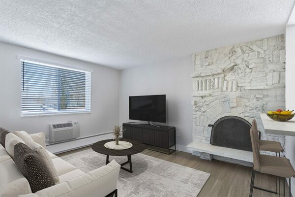Apartment living room with modern furniture, large TV, and fireplace.