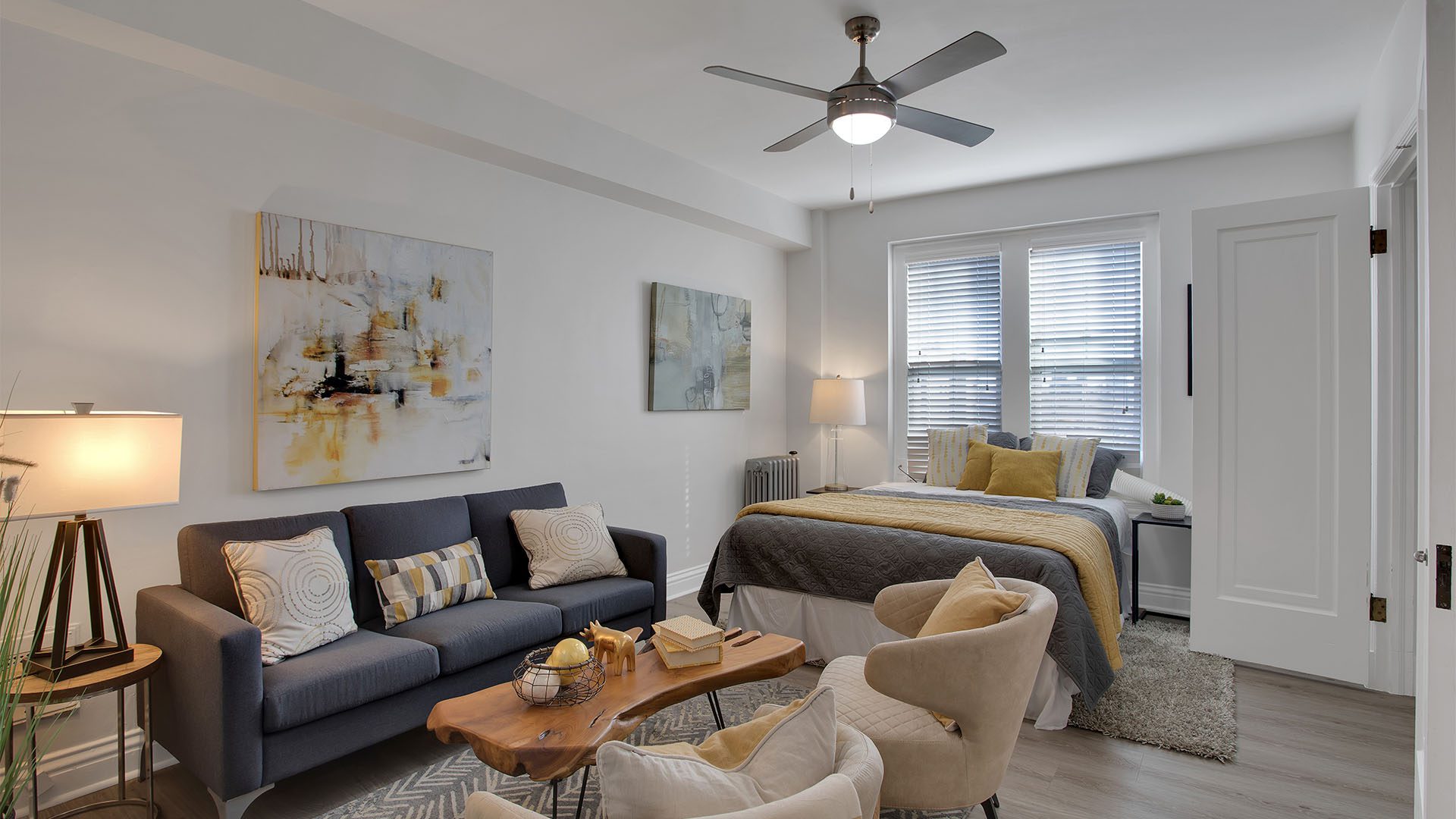 Studio living area with plush seating, large bed, and artwork.