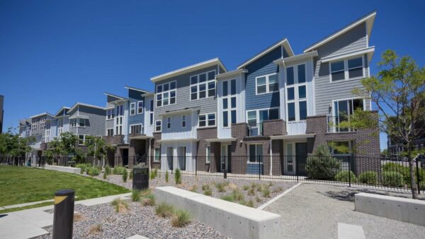 Platt Park townhomes with lush green lawns, iron fence, tall trees, and outdoor seating area.