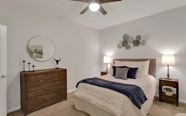 Apartment bedroom with queen size bed and dresser.