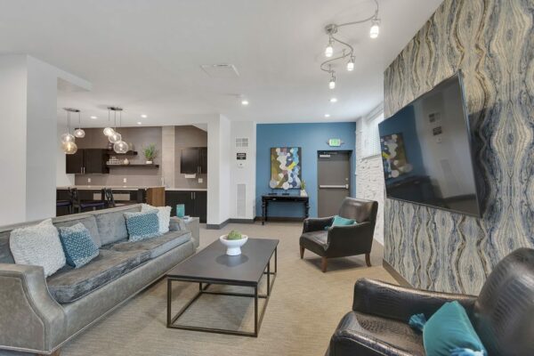 Lounge with plush seating, wall mounted TV, and demo kitchen.