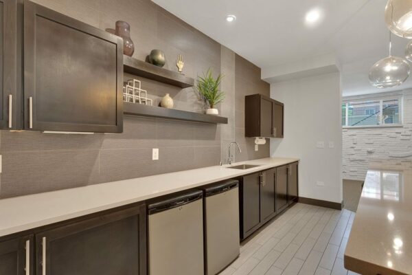 Demo kitchen with tile floor, stone counters, dark cabinets, and stainless steel appliances.
