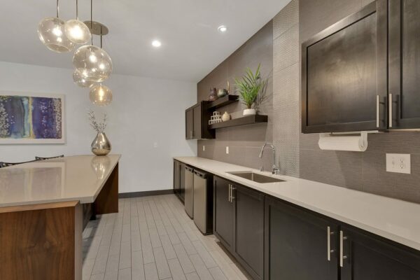 Demo kitchen with tile floor, stone counters, dark cabinets, and stainless steel appliances.