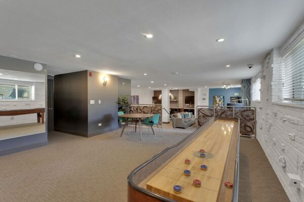 Lounge with shuffleboard, table, and brick accent wall.