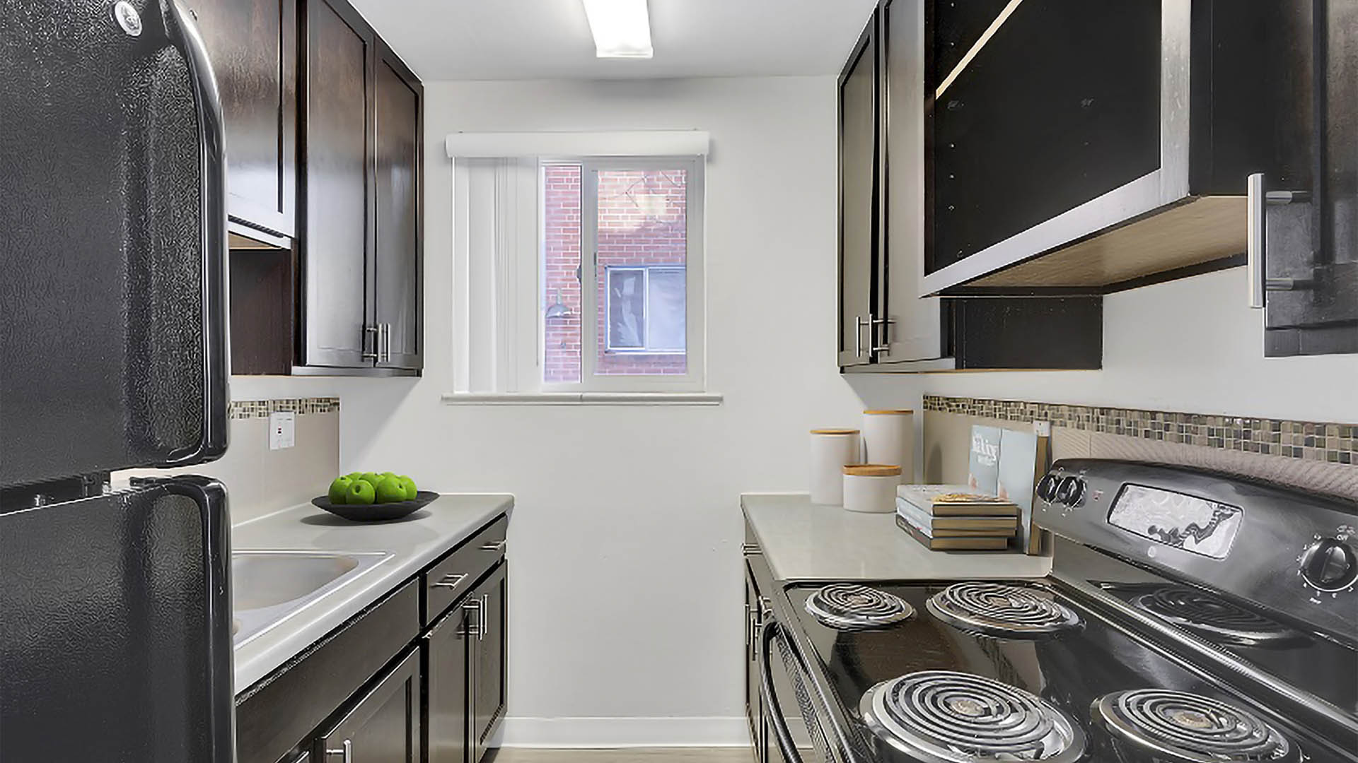 Kitchen with dark cabinets, light counters, and stainless steel appliances.