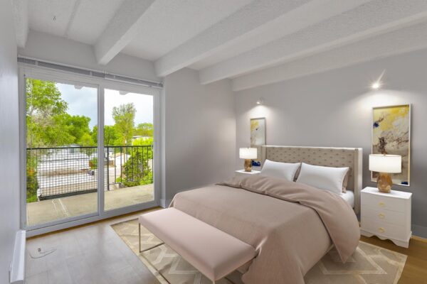 Bedroom with rug, large bed, bedside tables with lamps, and door to balcony.
