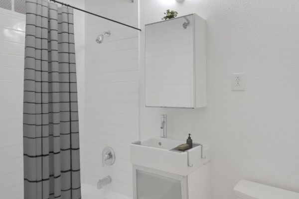 bathroom with white cabinets and sink with toilet on the right and bath tub on the left