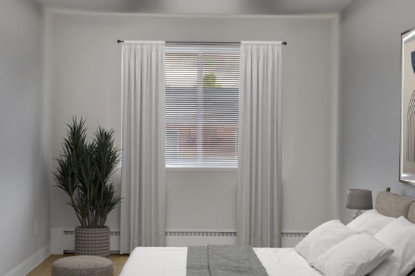 bedroom with bed in the center, curtains on window and plant in corner