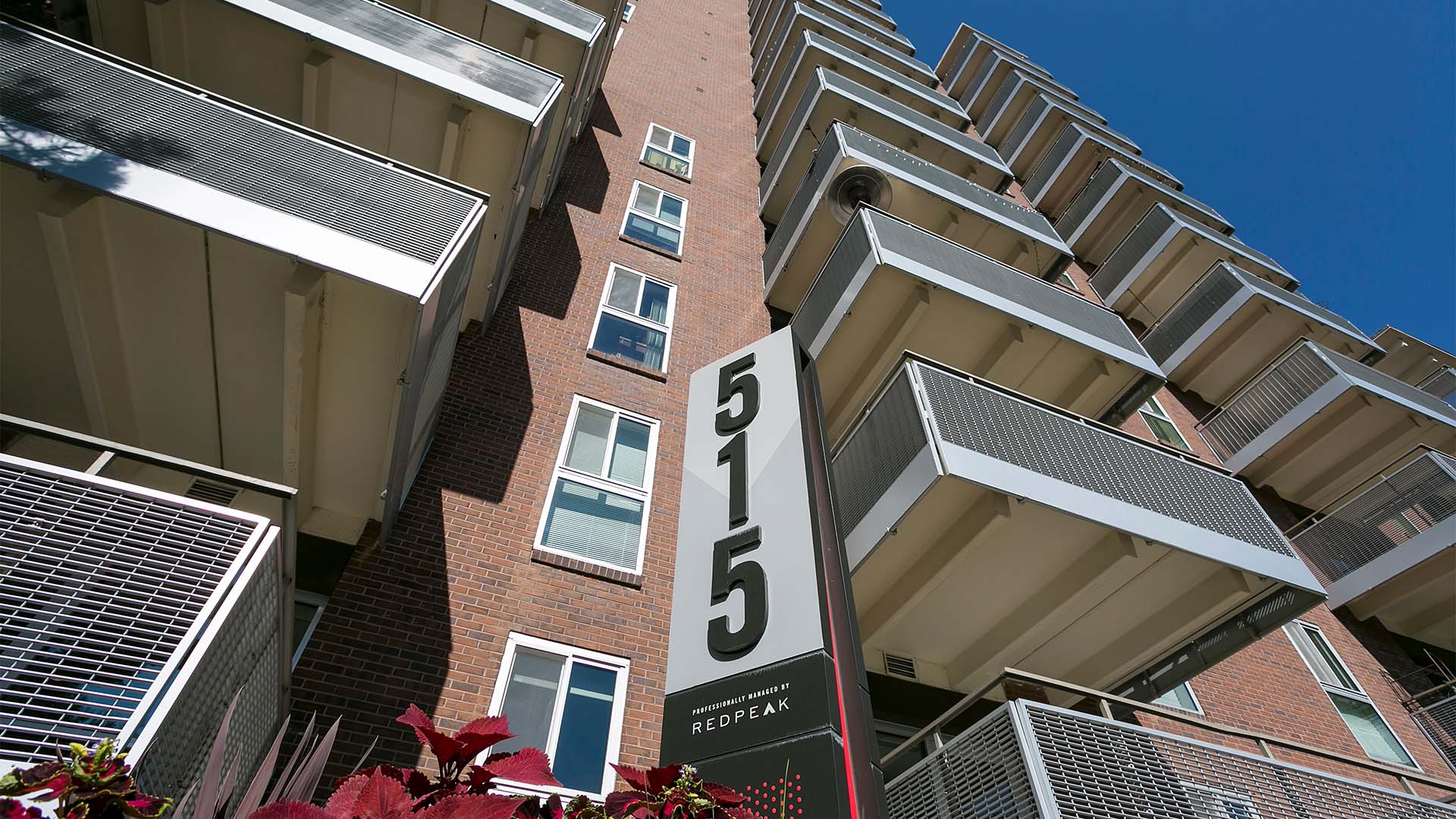 515 Clarkson apartments with brick construction, large balconies, and monument sign.