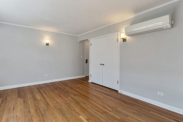 Bedroom with wood floor, cool gray walls with white trim, and large closet.