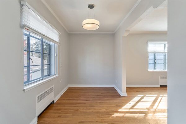 Living room with wood floor, cool gray walls, lighting fixture, and large windows.