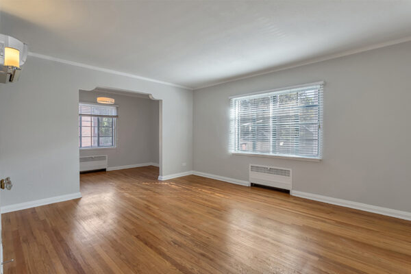 Living room with wood floors, cool gray walls, and large windows.