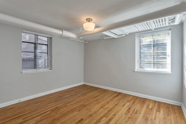 Bedroom with wood floor, cool gray walls with white trim, and large windows.
