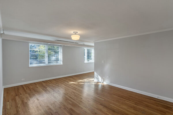 Living room with wood floors, cool gray walls with white trim, and large windows.