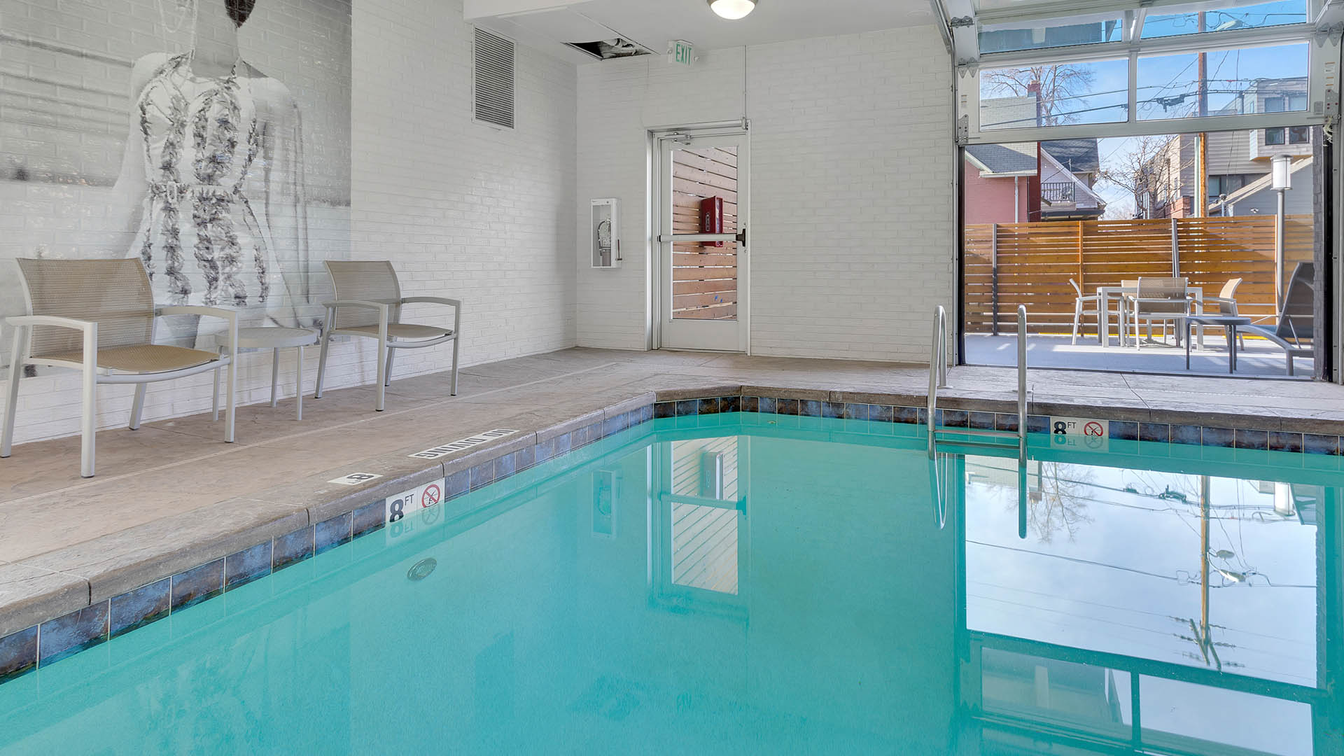 Indoor pool with chairs and garage door to patio.