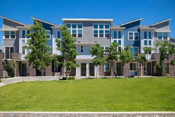 Platt Park townhomes with lush green lawns, iron fence, and tall trees.