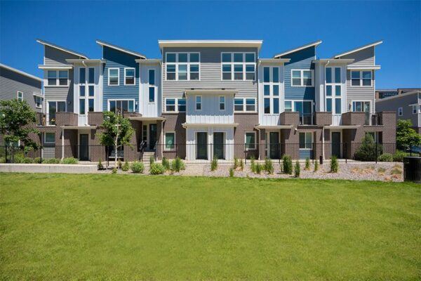 Platt Park townhomes with lush green lawns, iron fence, and tall trees.