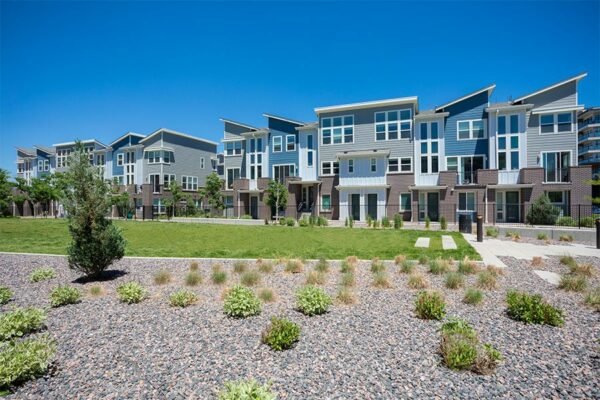 Platt Park townhomes with lush green lawns, iron fence, and rocky landscaping.
