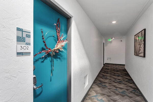 Hallway outside apartment 302 with door decoration and geometric carpet.