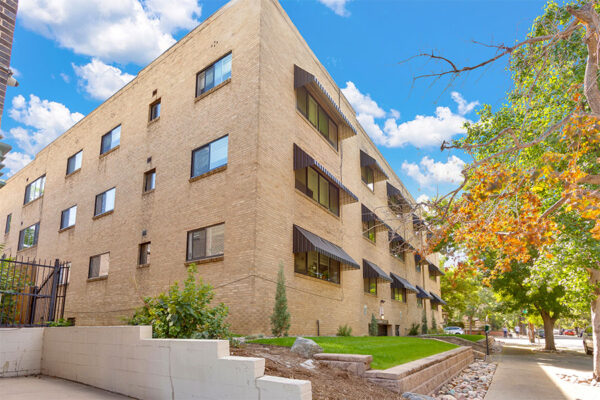 611 East 11th exterior with blond brick construction with rocky landscaping and tall trees.