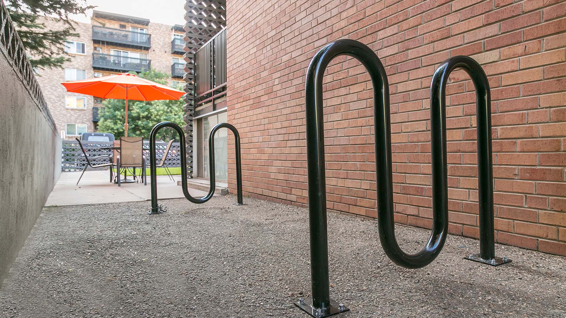 Bike racks and patio furniture next to brick apartment building.