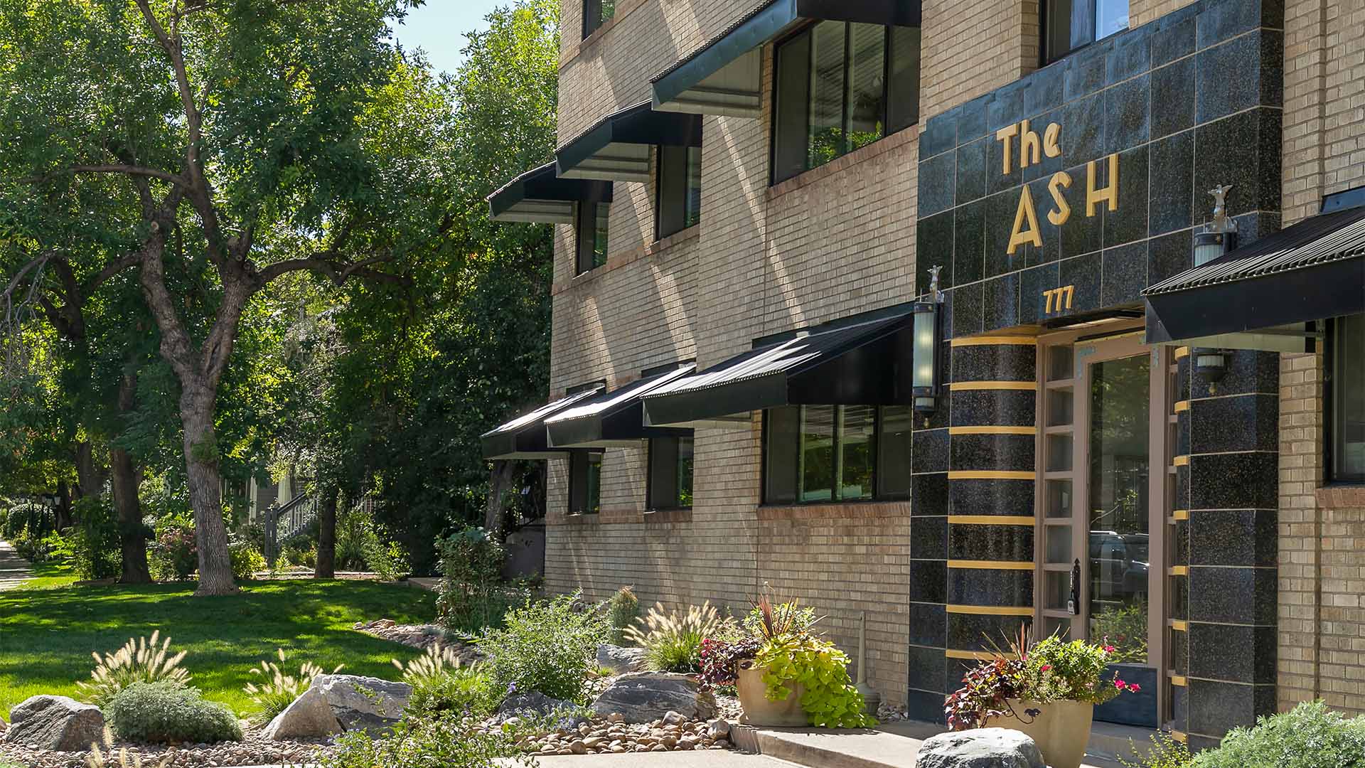 777 Ash apartment building with blonde brick construction and art deco style entrance.