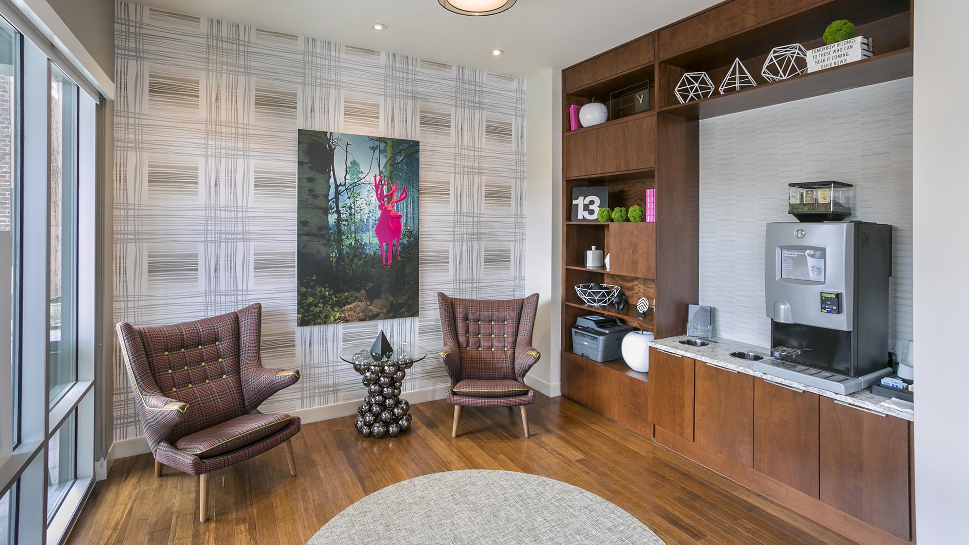Lounge with coffee machine, shelves with decor, eclectic chairs and colorful artwork.