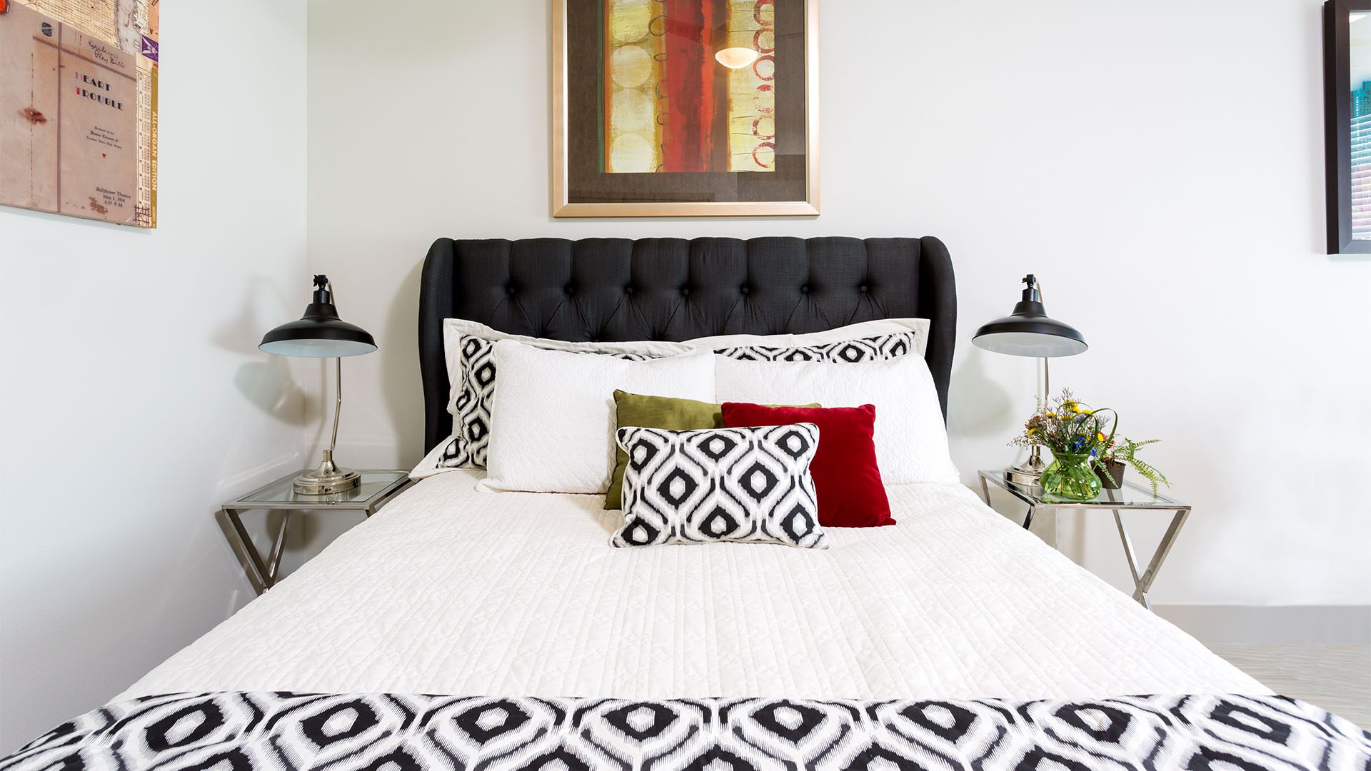 Bedroom with bed with plush headboard, modern metal side tables with lamps, and framed wall art.