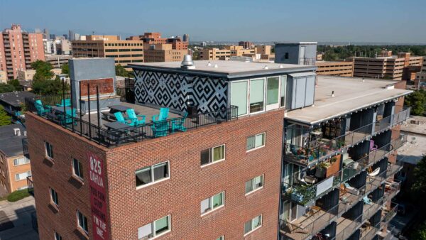 Aerial view of 825 Dahlia apartments with brick construction, large balconies, and rooftop patio.