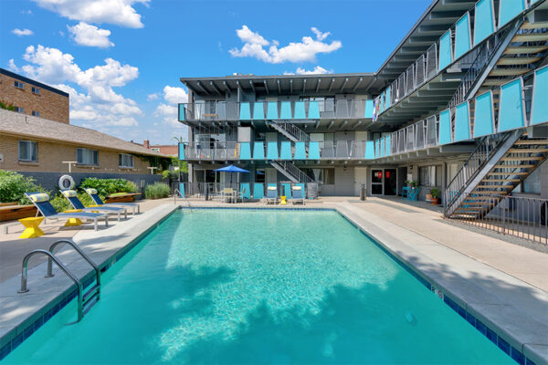 Pool area with bright blue water overlooked by apartment balconies.