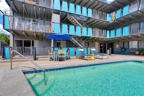Pool area with lounge chairs and tables overlooked by apartment balconies.