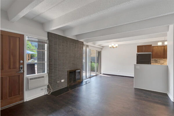 Living area with wood floor, brick accent wall with fireplace, and door to balcony.