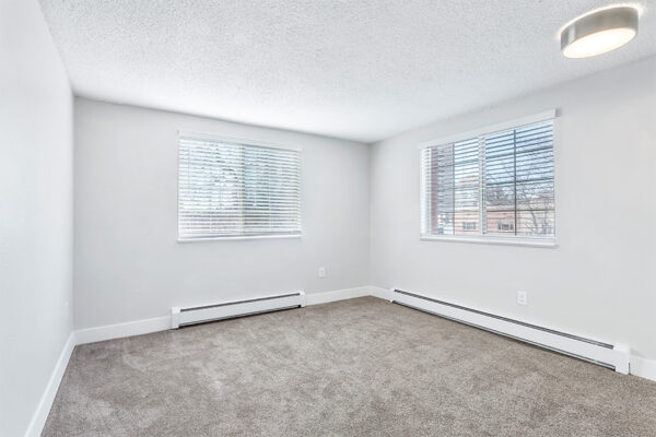 Bedroom with carpet, baseboard heaters, cool gray walls, and large windows.