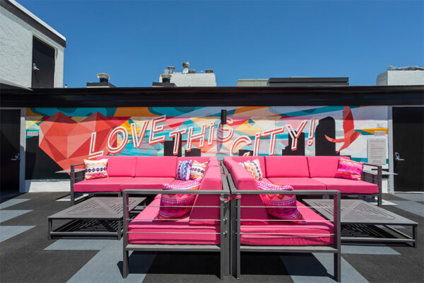 Rooftop patio with outdoor couches and mural art.