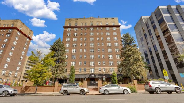 960 Grant apartments with classic two tone brick construction, mature trees, and street parking.