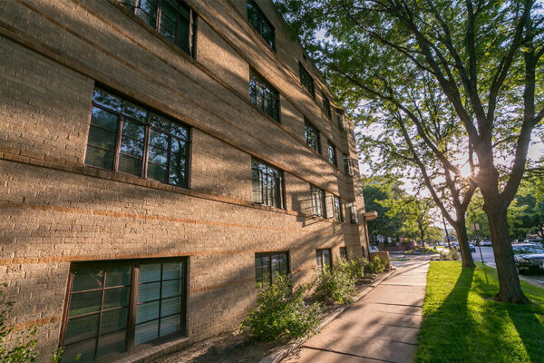 970 Penn apartment building with blonde brick construction and sunlight streaming through trees.