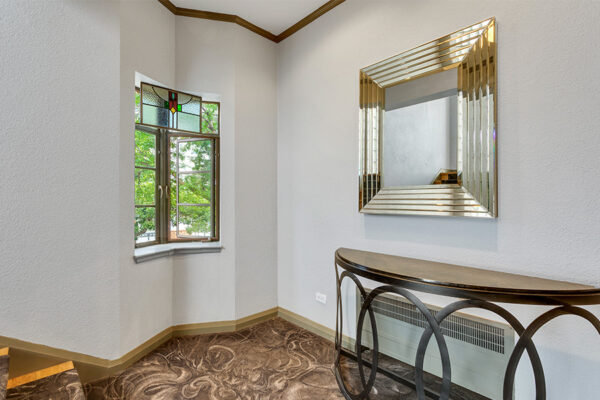 Lounge with decorative carpet and classic stained glass window.