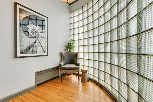 Lounge with round glass brick wall and wingback chair.