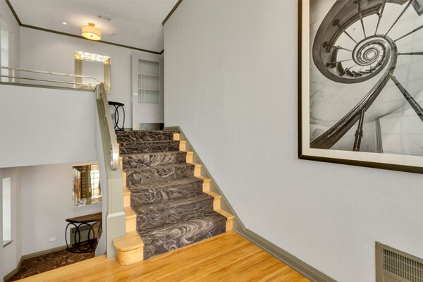 Stairwell with illustrated carpet, wall art, and bright natural light.