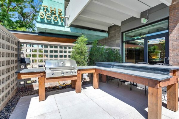Outdoor lounge with comfortable seating, fire pit, and apartment balconies.