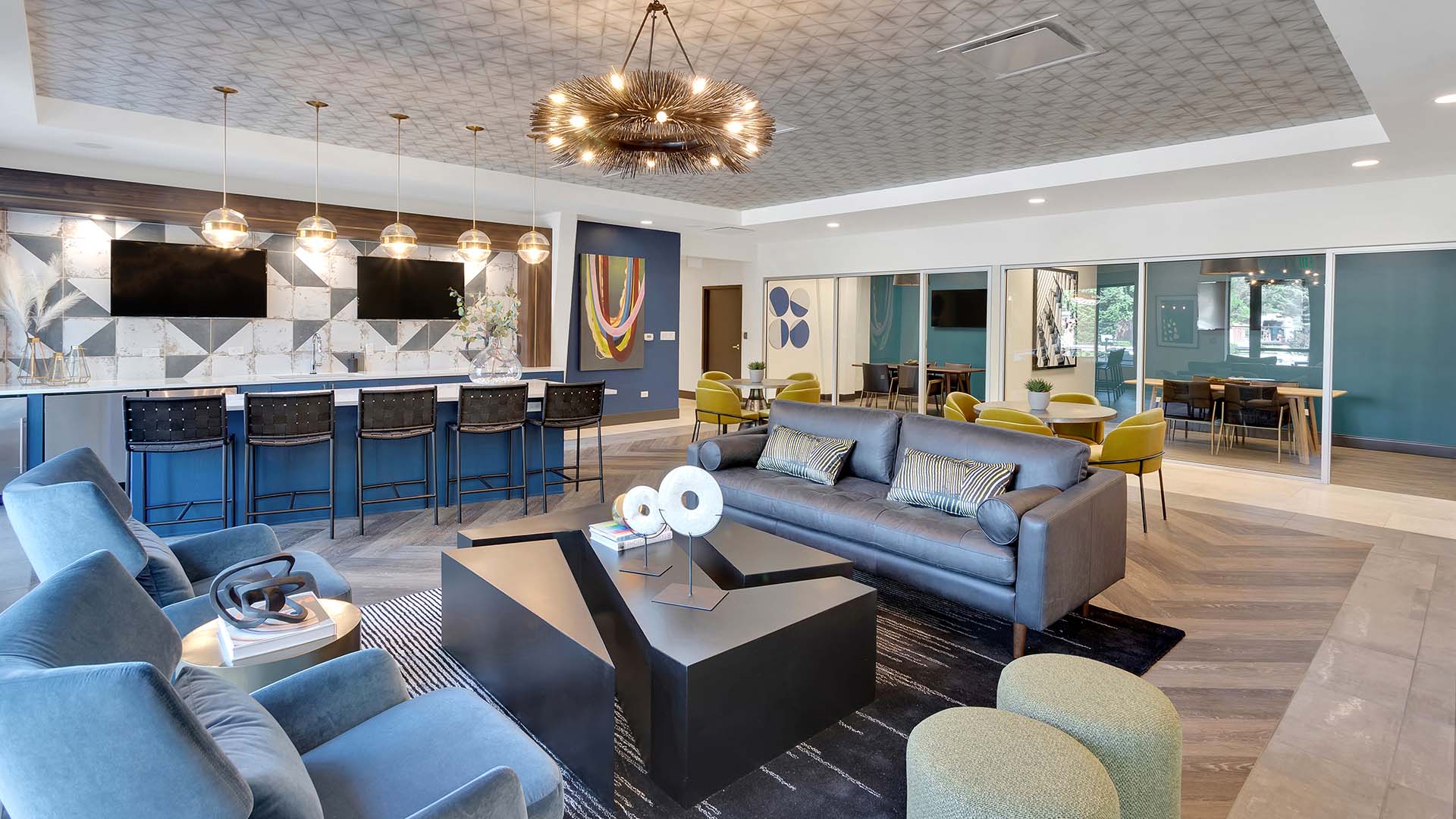 Lounge with wood floor, plush seating, modern furniture, breakfast bar, and decorative lighting fixture.