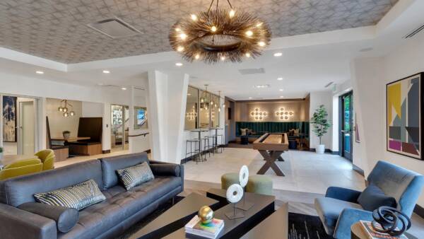 Clubhouse with plush leather seats, eclectic modern decor, shuffleboard table, and seating booths.