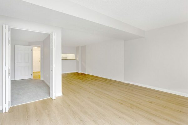 Living area with wood floor, grey walls, white trim, and door to bedroom.