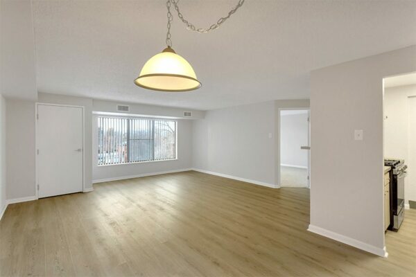 Living area with wood floor, grey walls, white trim, and doors to bedroom and kitchen.