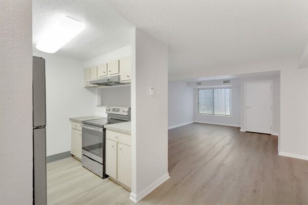 Living area with wood floor, grey walls, white trim, and doors to outside and kitchen.