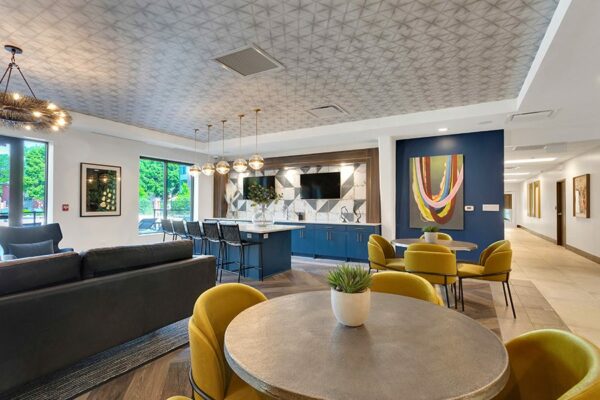 Lounge with wood floor, round dining tables, large couches, breakfast bar, and wall mounted TVs.