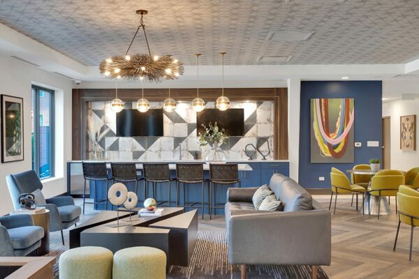 Lounge and community kitchen with modern furniture, decorative lighting fixtures, breakfast bar, and wall art.