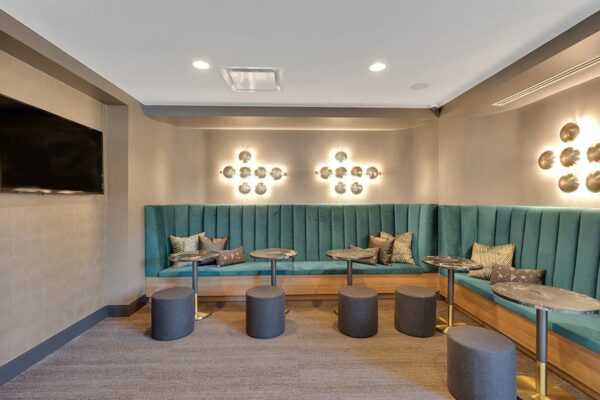 Lounge with plush booths, pillows, decorative lighting fixtures, and wall mounted TV.